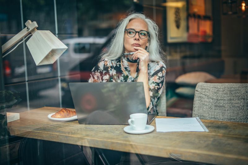 old businesswoman sitting in a cafe alone thinking deeply